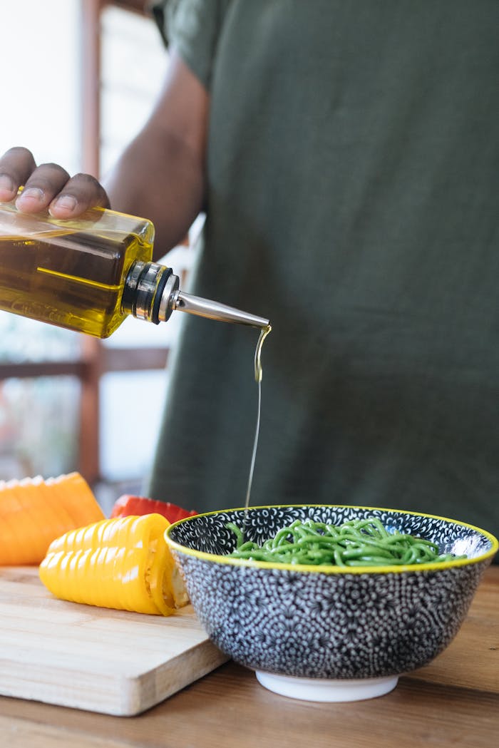 Close-up of fresh vegetable salad with olive oil pouring from a bottle, highlighting healthy eating.