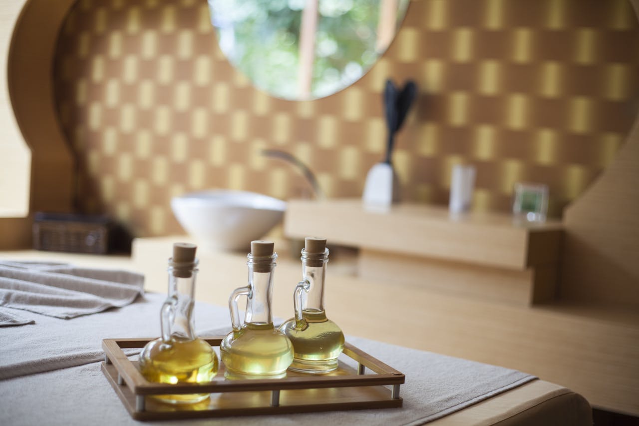 Elegant indoor spa room with natural oil bottles on a wooden tray, exuding relaxation.